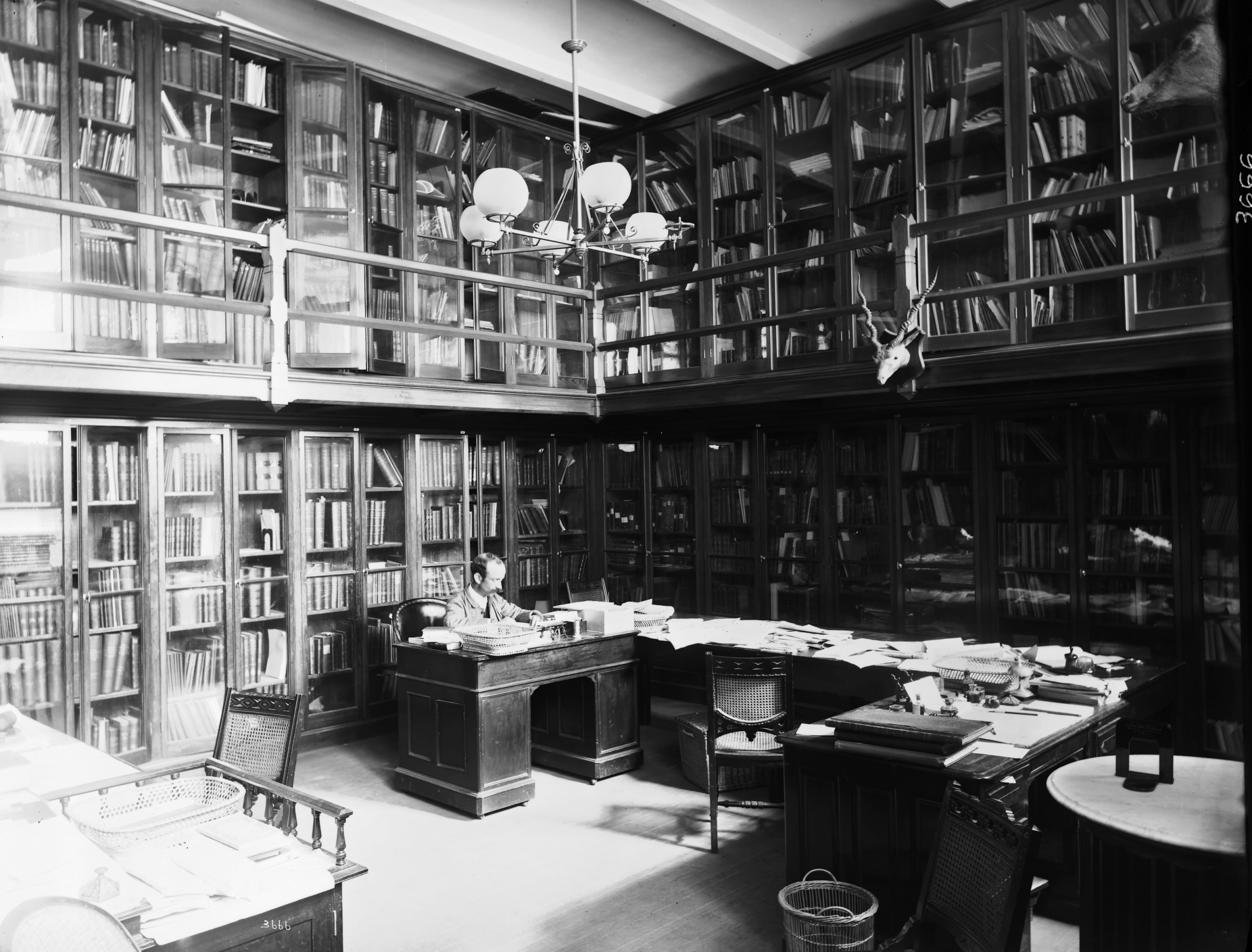 Large library with multiple floors. A man sits at a desk in the center.