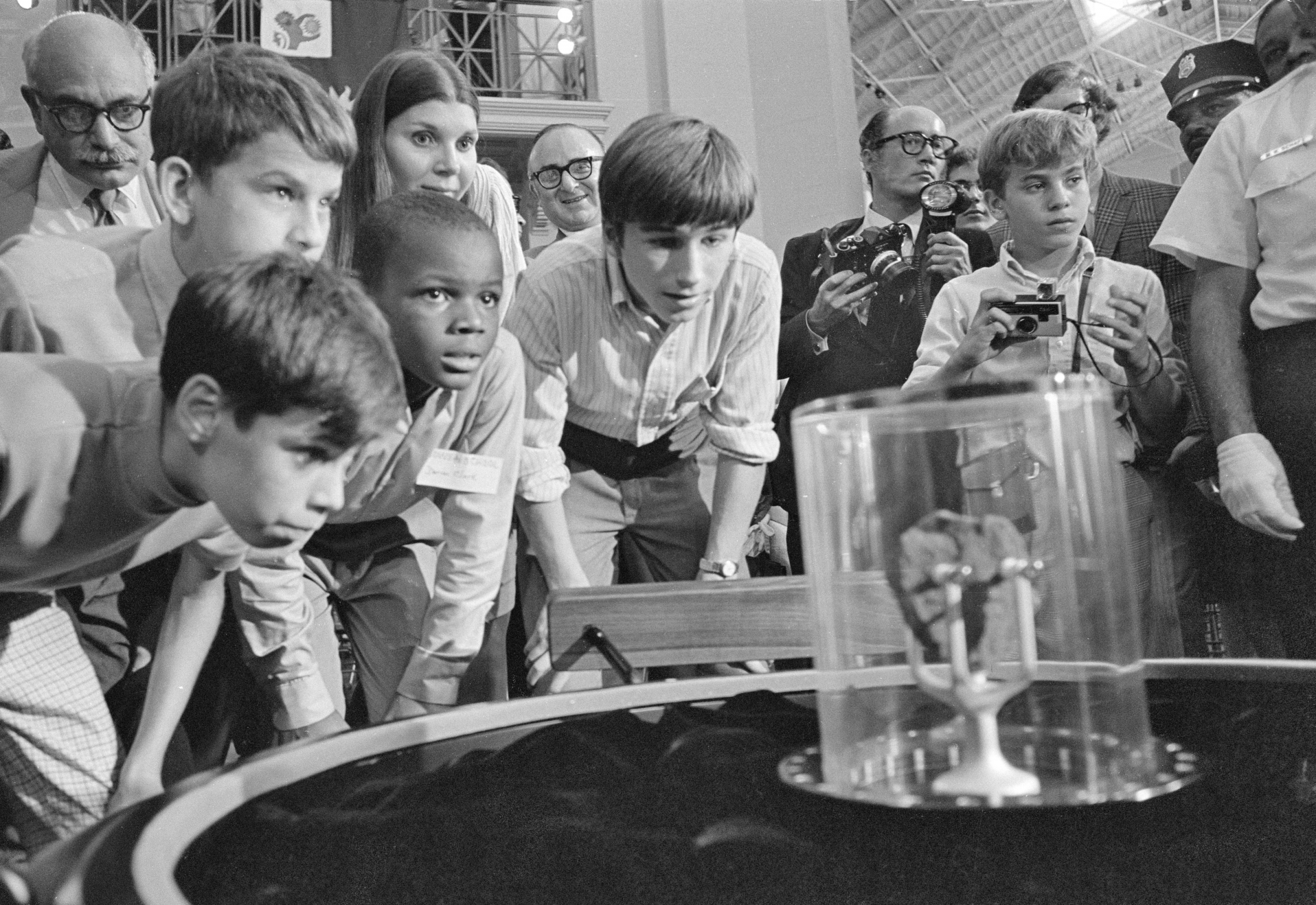 Group of people gathered around a rock in a glass case