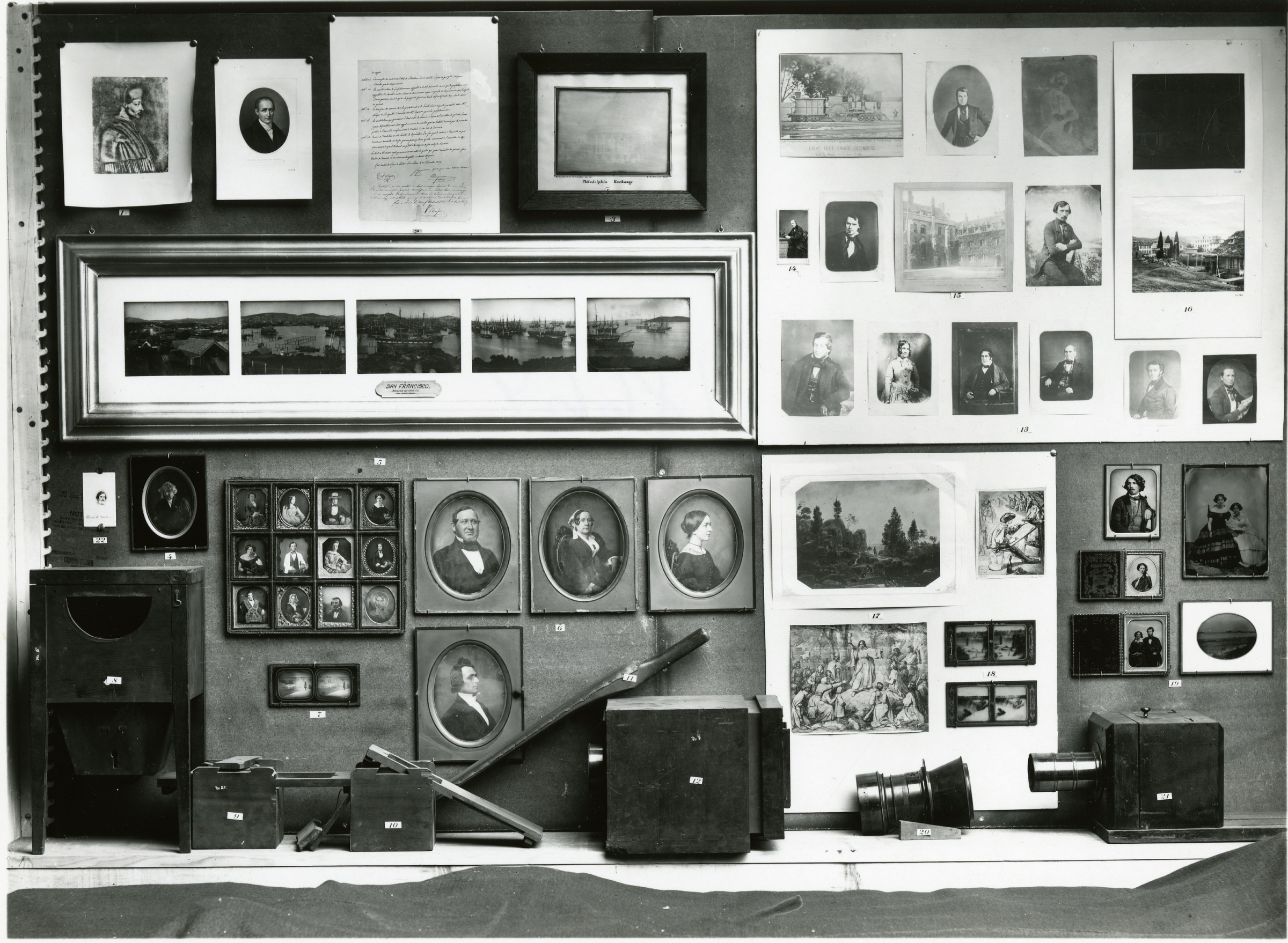 Exhibit of many photographs in frames. There are old cameras in front.