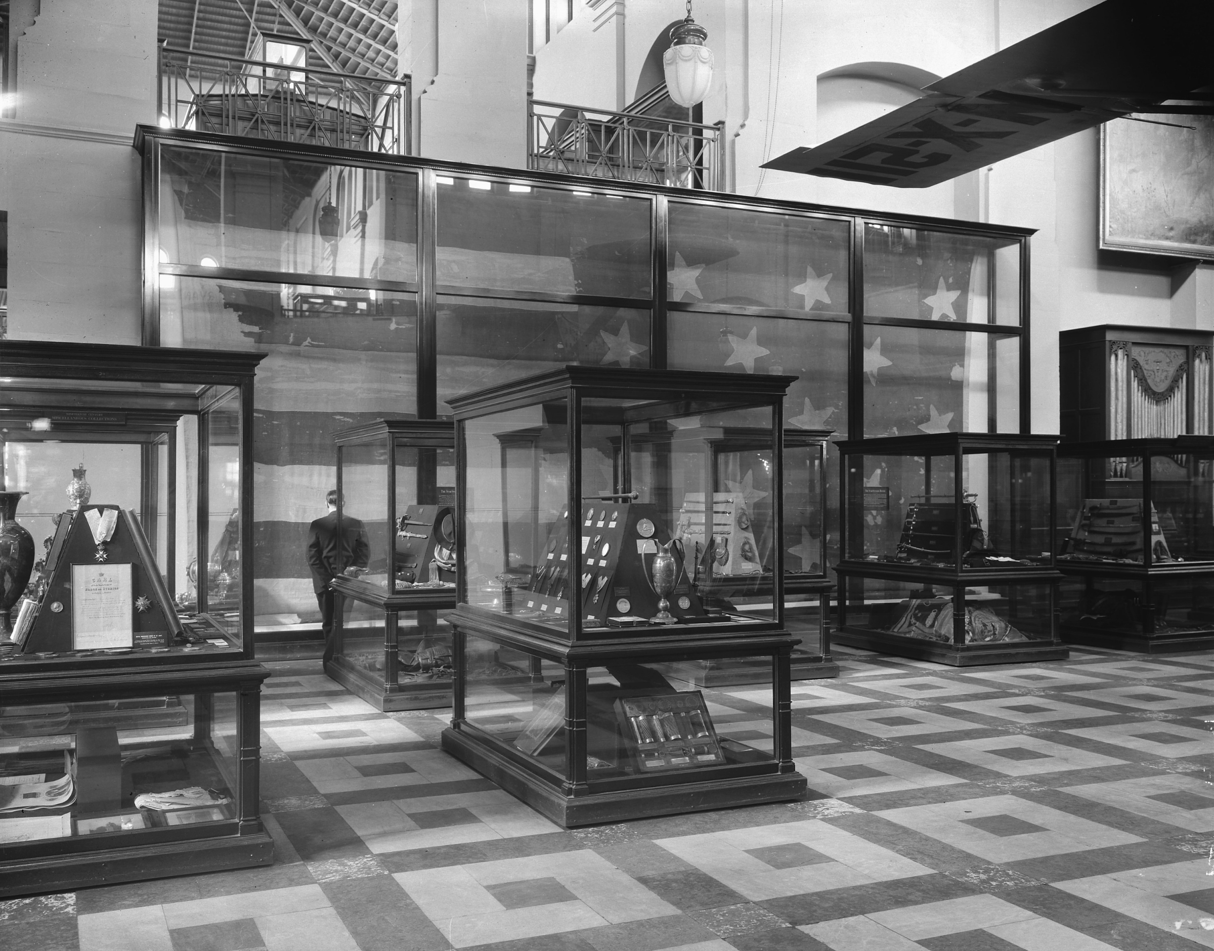 Museum hall filled with exhibit cases. There is an American flag on the far wall.