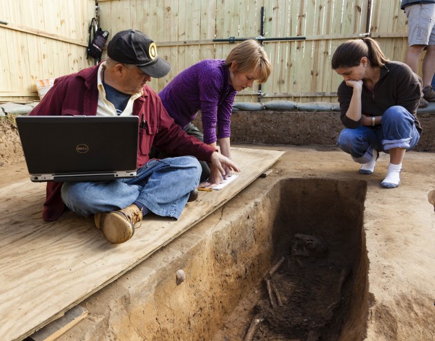 Smithsonian forensic anthropologists Doug Owsley and Kari Bruwelheide and colleague Ashley McKeown examine the grave of Rev. Robert Hunt. (Photo by Donald Hurlbert)