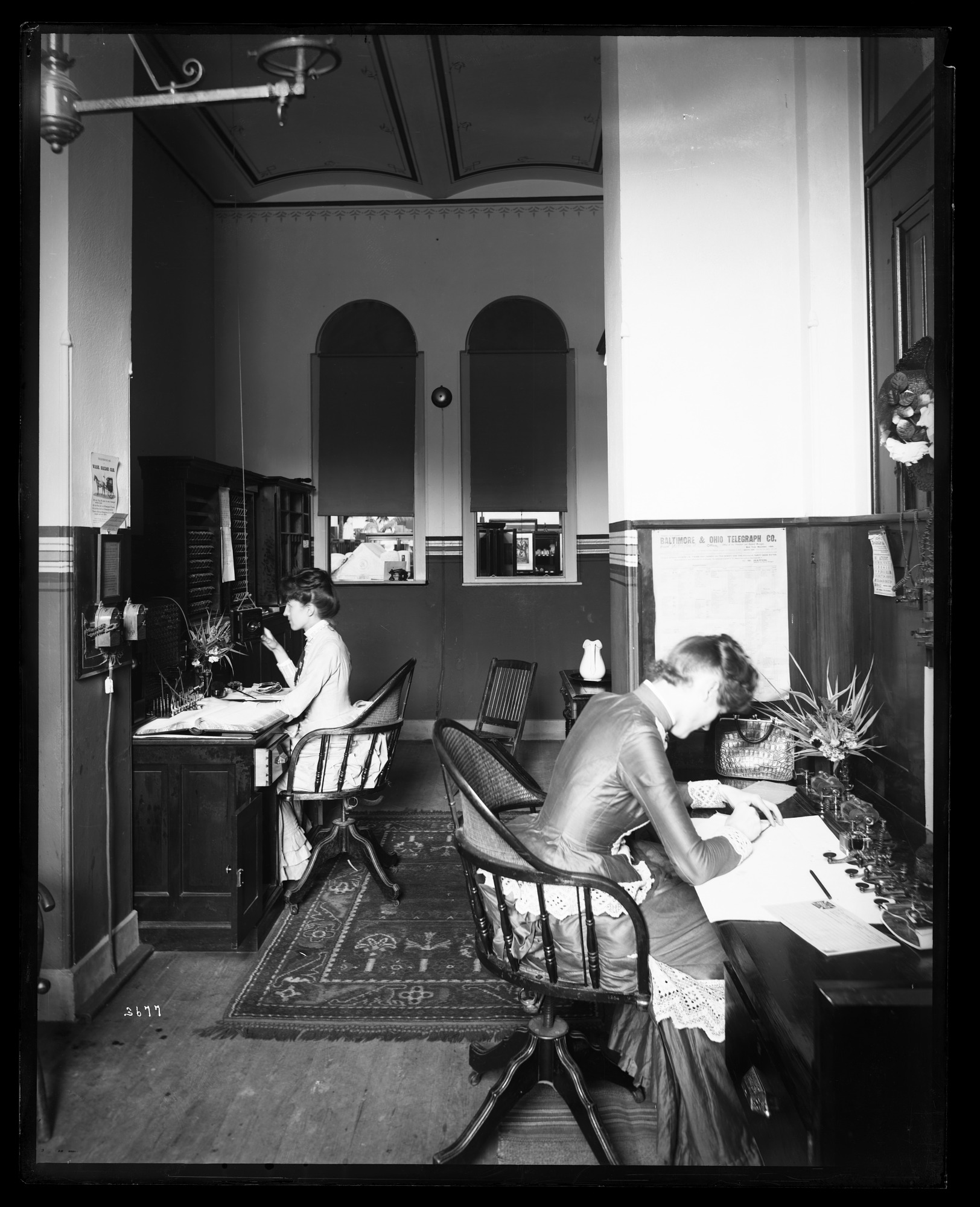 Black and white photo of women working in a room with telegraphs