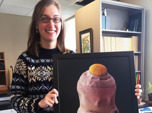 Woman holding an image of a tapeworm.