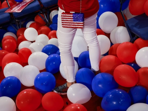 woman with American flag purse surrounded by red and blue balloons