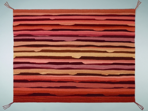 Image of flat tapestry with horizontal stripes in varying shades of orange, yellow, pink and red.