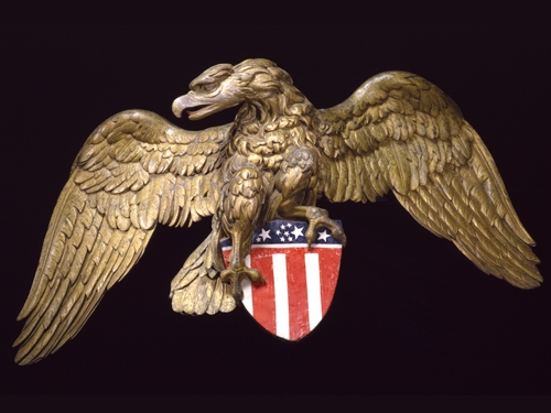 A bronze eagle holding a US flag pin.