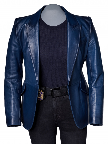 Image of an outfit on mannequin, blue leather jacket over black top and jeans with police badge at waist.