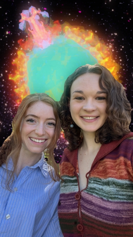 Two women stand next to each other smiling, with a graphic projection of a colorful blue and orange circular star in background.