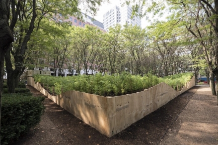 Picture of planting area with green grass and trees inside.